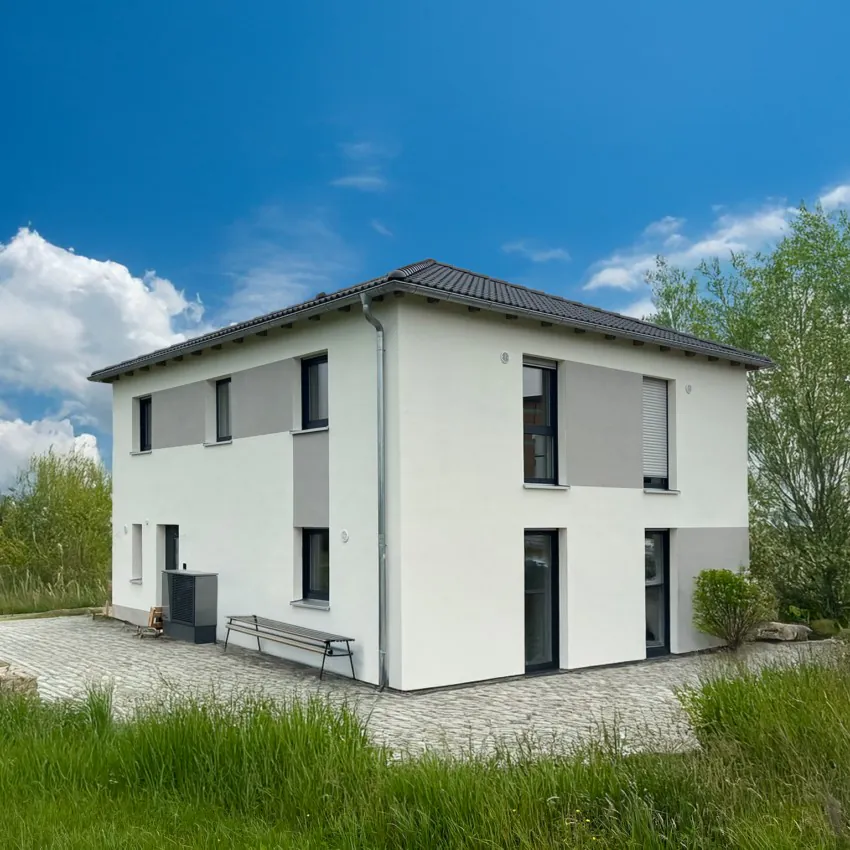 Zweistöckiges weißes Haus bei sonnigem Wetter.