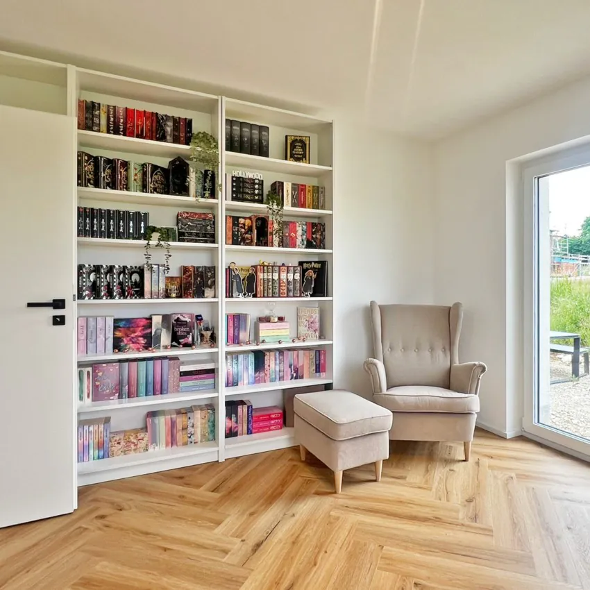 Bücherregal mit Sessel in einem hellen Raum.