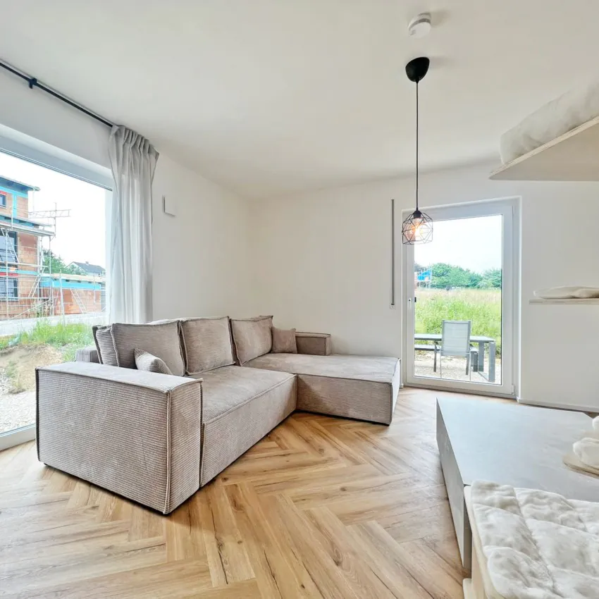 Wohnzimmer mit Ecksofa und großem Fenster.