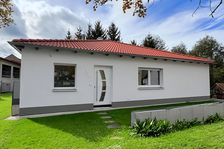 Ein einstöckiges weißes Haus mit rotem Dach.