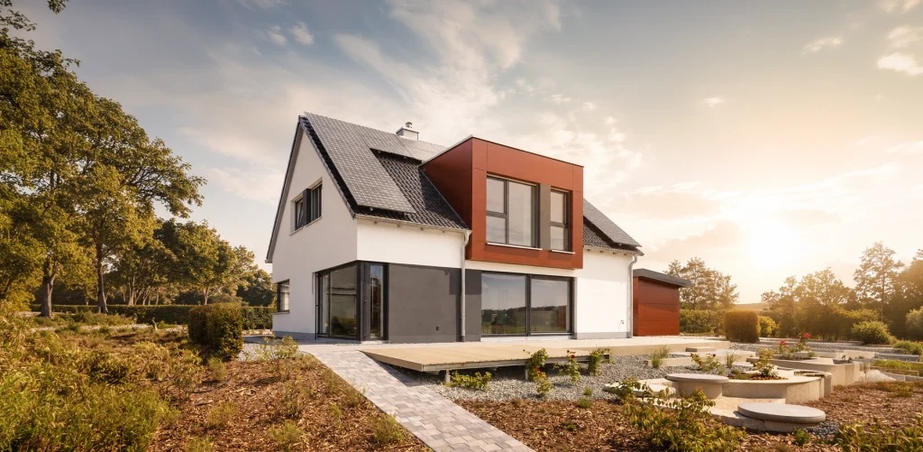 Perspektivansicht des Musterhauses Easy mit modernem Satteldach, markantem Erker in Holzoptik, Photovoltaikanlage und großzügiger Terrasse.