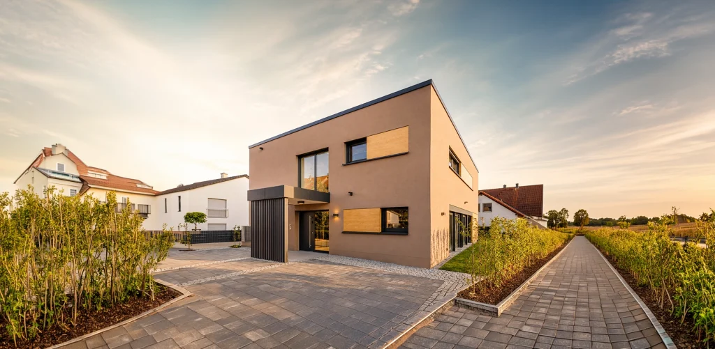 Die konsequent kubische Architektur mit Flachdach, großen Fensterflächen und markanten Fassadenelementen verkörpert modernes Wohnen in seiner klarsten Form.