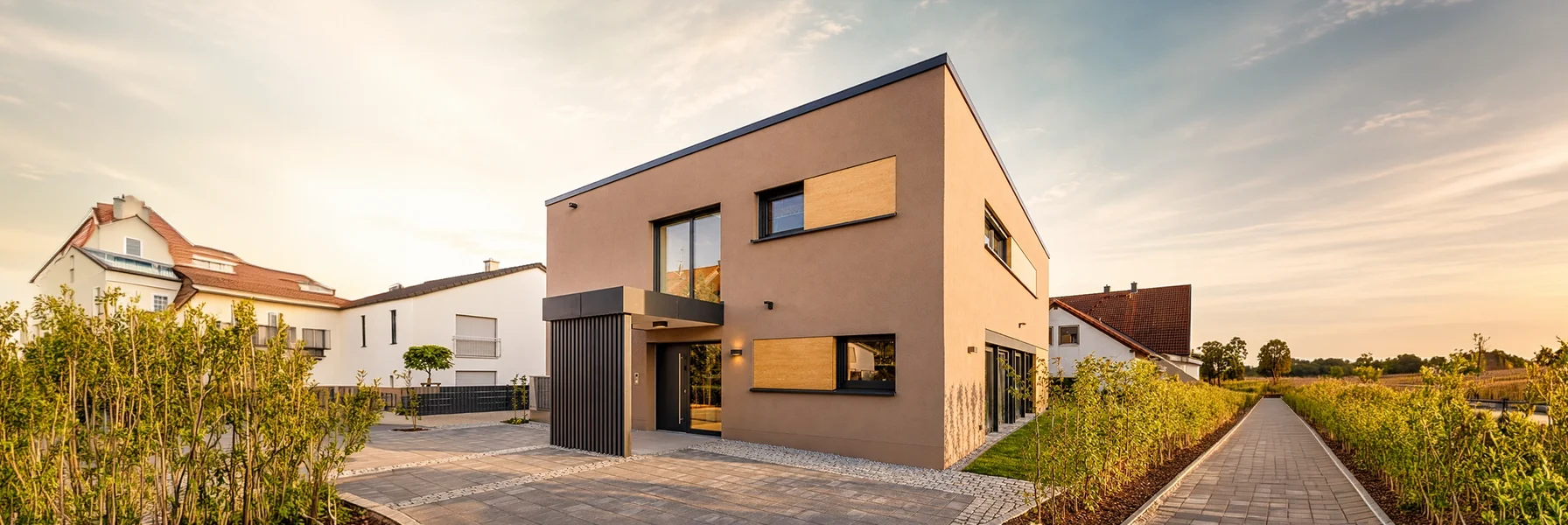 Die konsequent kubische Architektur mit Flachdach, großen Fensterflächen und markanten Fassadenelementen verkörpert modernes Wohnen in seiner klarsten Form.