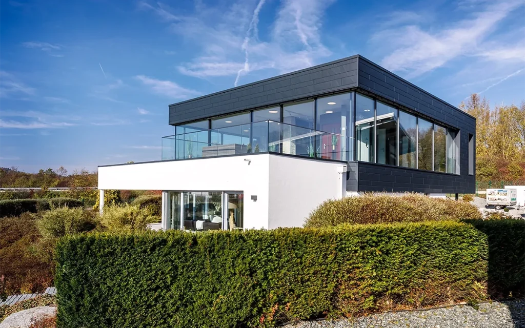 Modernes zweistöckiges Gebäude mit Glasfassade und Garten.