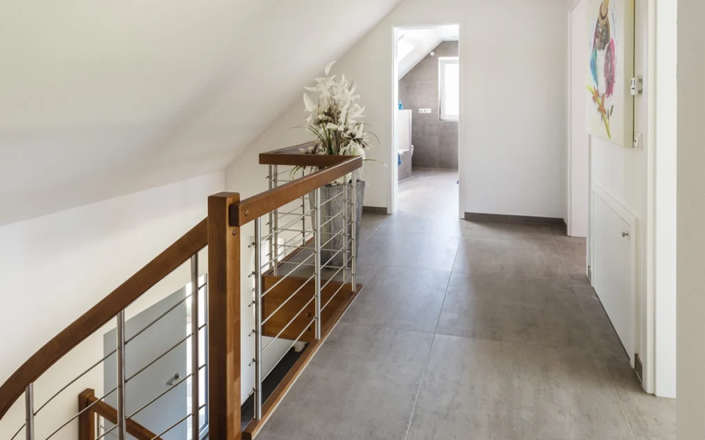 Flur mit Treppengeländer und Blumengesteck.