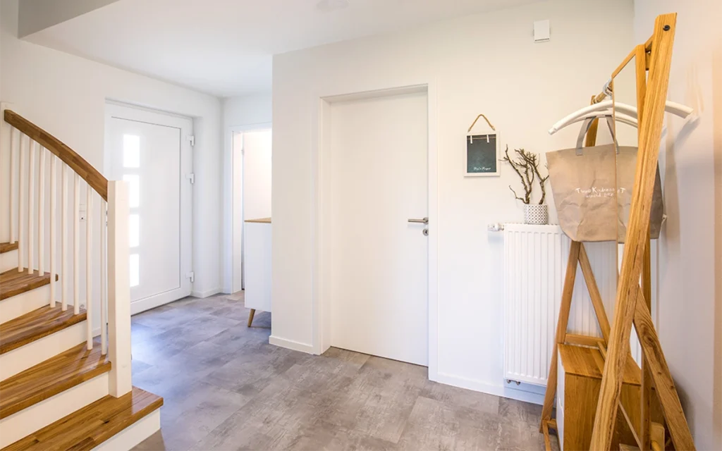 Treppenhaus mit Holztreppe und heller Einrichtung.