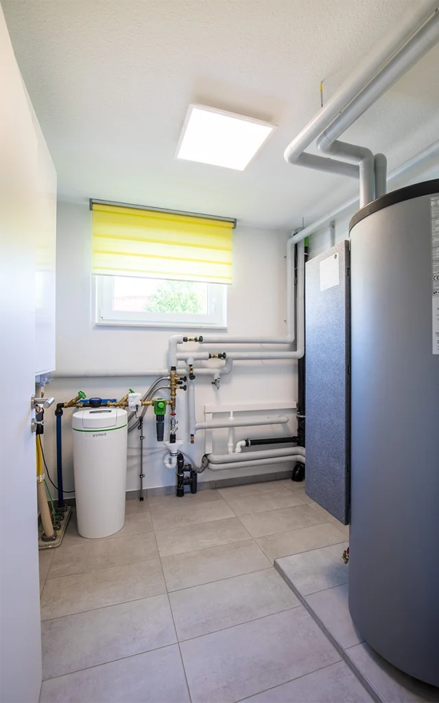 Heizungsraum mit Rohren und Geräten.