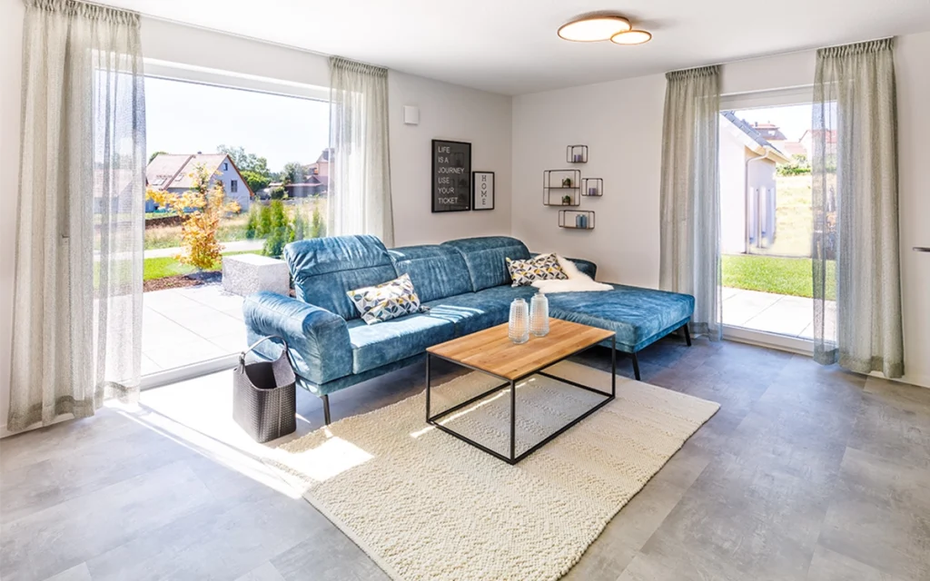 Wohnzimmer mit blauer Couch und großem Fenster.