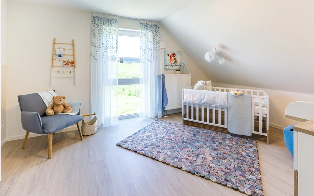 "Modernes Babyzimmer mit Bett, Teppich und Stuhl."