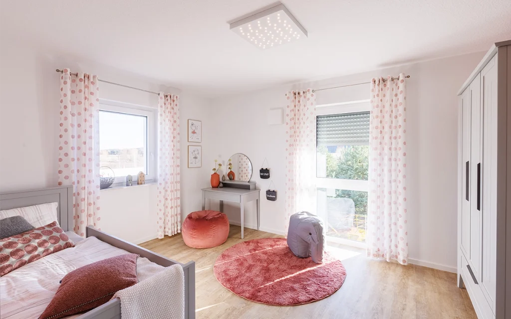 Helles Kinderzimmer mit Bett, Teppich und Fenster.