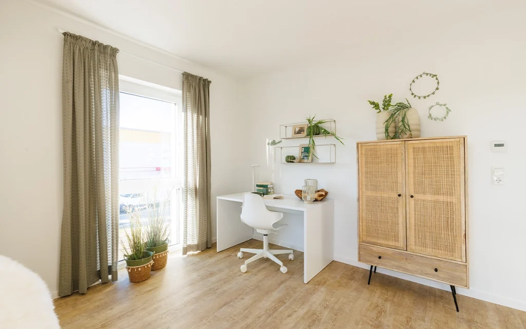 Helles Arbeitszimmer mit Schreibtisch und Regal.