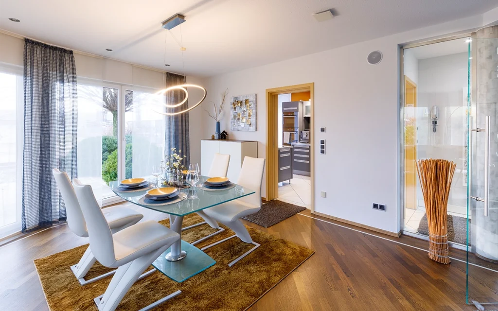 Esszimmer mit modernem Glastisch und weißen Stühlen.