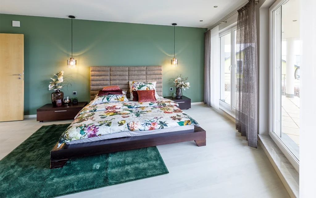 Schlafzimmer mit grünem Akzent und floralem Bettzeug.