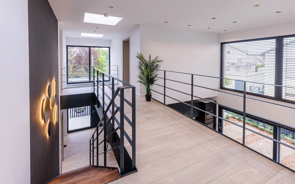 Modernes Treppenhaus mit großen Fenstern und Pflanzen.