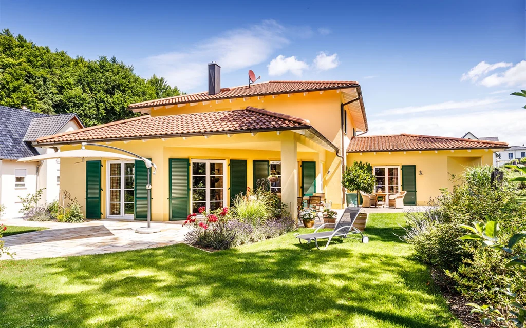 Gelbes Haus mit Garten und Terrasse.
