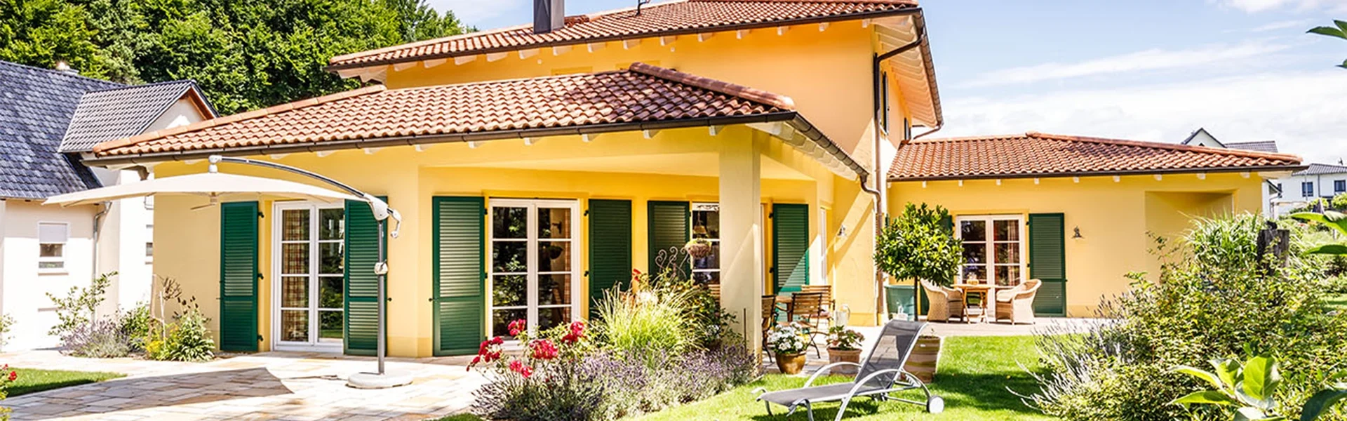 Gelbes Haus mit Garten und Terrasse.