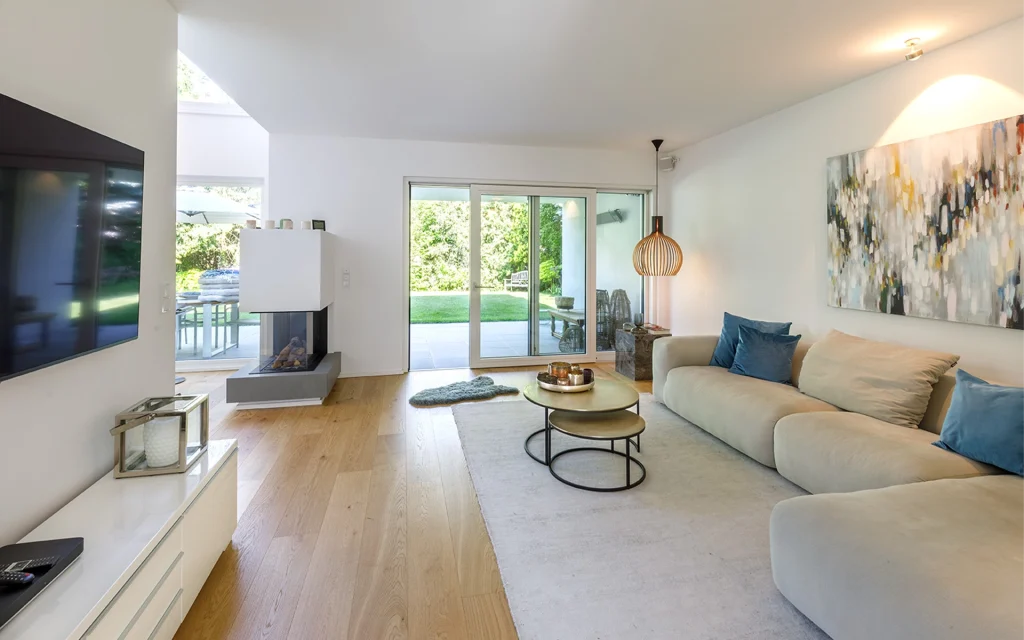 Modernes Wohnzimmer mit großem Sofa und Glastüren zum Garten.