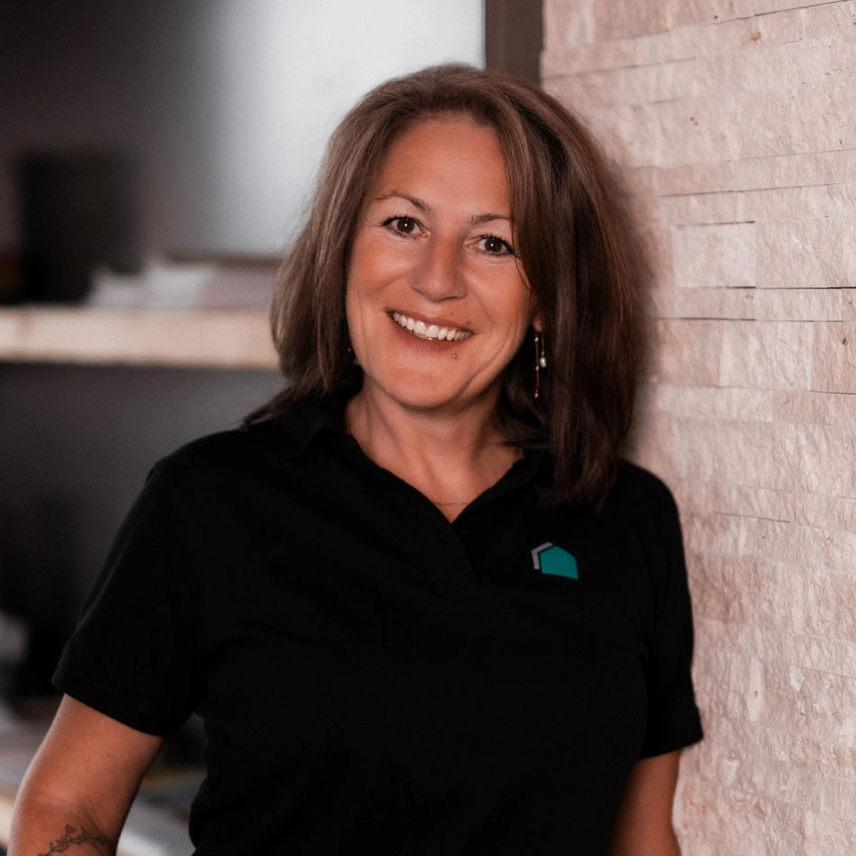 Anja lächelnd vor einer Steinwand.