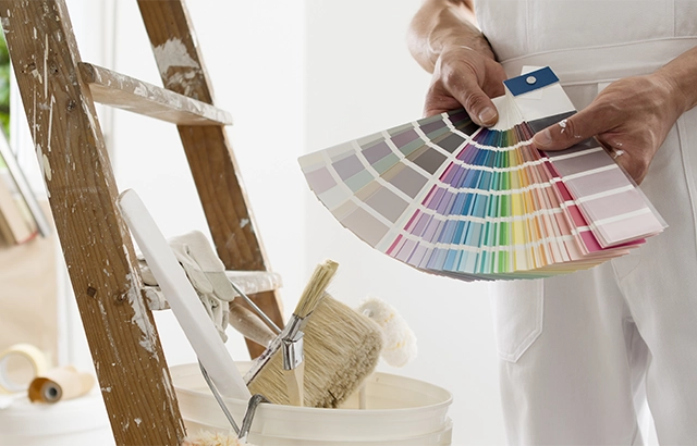 "Malerarbeiten, Farbfächer und Leiter."