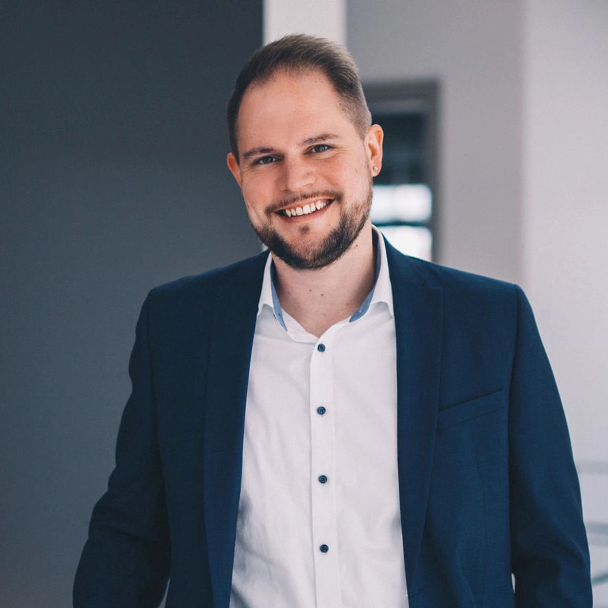 Bauberater Patrick im Anzug lächelt.