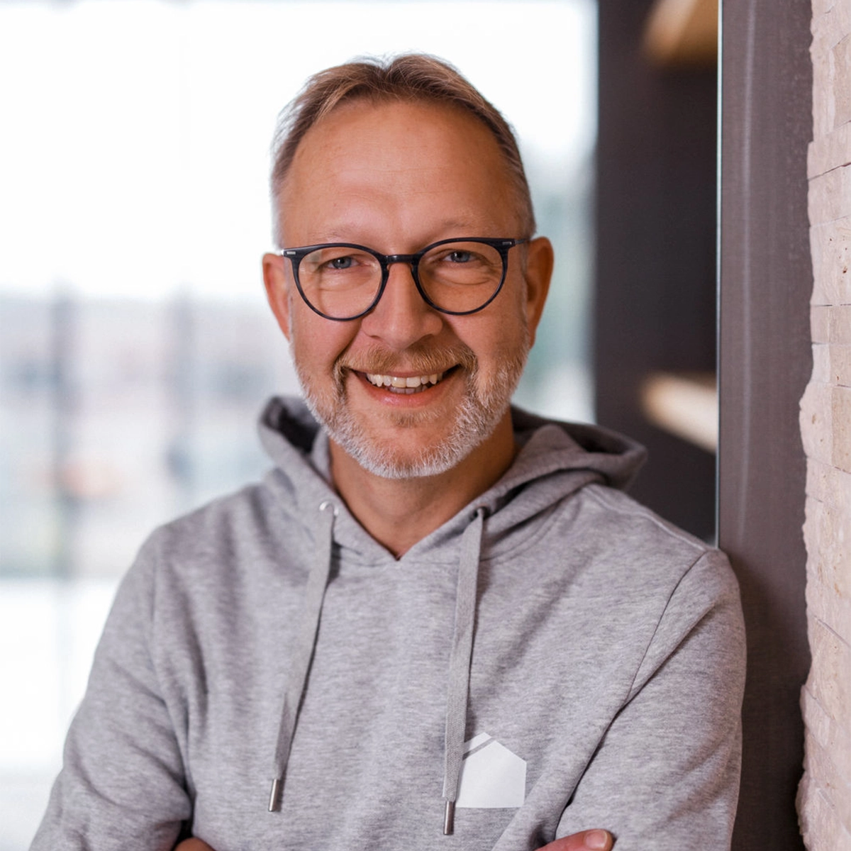 Roland lächelt, trägt Brille und grauen Hoodie.