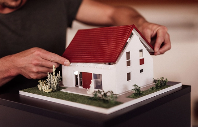 Person stellt ein Modellhaus zusammen.