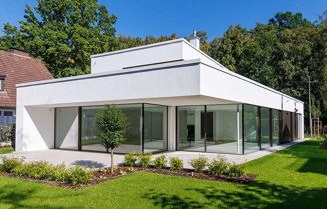 Modernes Gebäude mit Glasfronten und Garten.