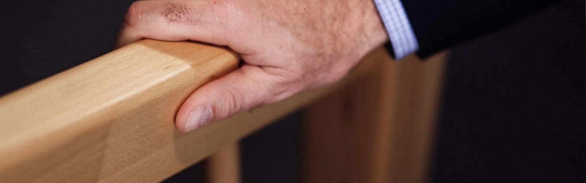 Hand auf einem Holzbalken.