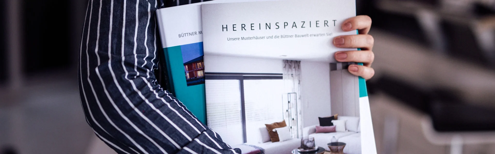 Person hält Broschüre mit dem Titel "Hereinspaziert".