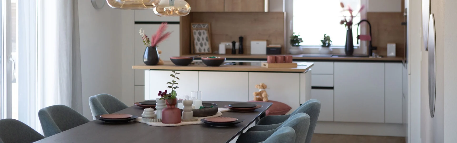 Esszimmer mit gedecktem Tisch und moderner Küche im Hintergrund.