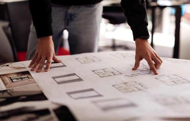 Person bei der Arbeit mit Bauplänen.