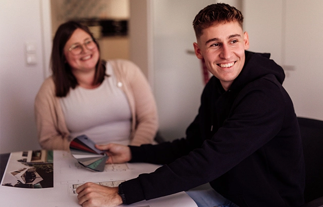 Linda und Manuel sitzen an einem Tisch mit Designmaterialien.
