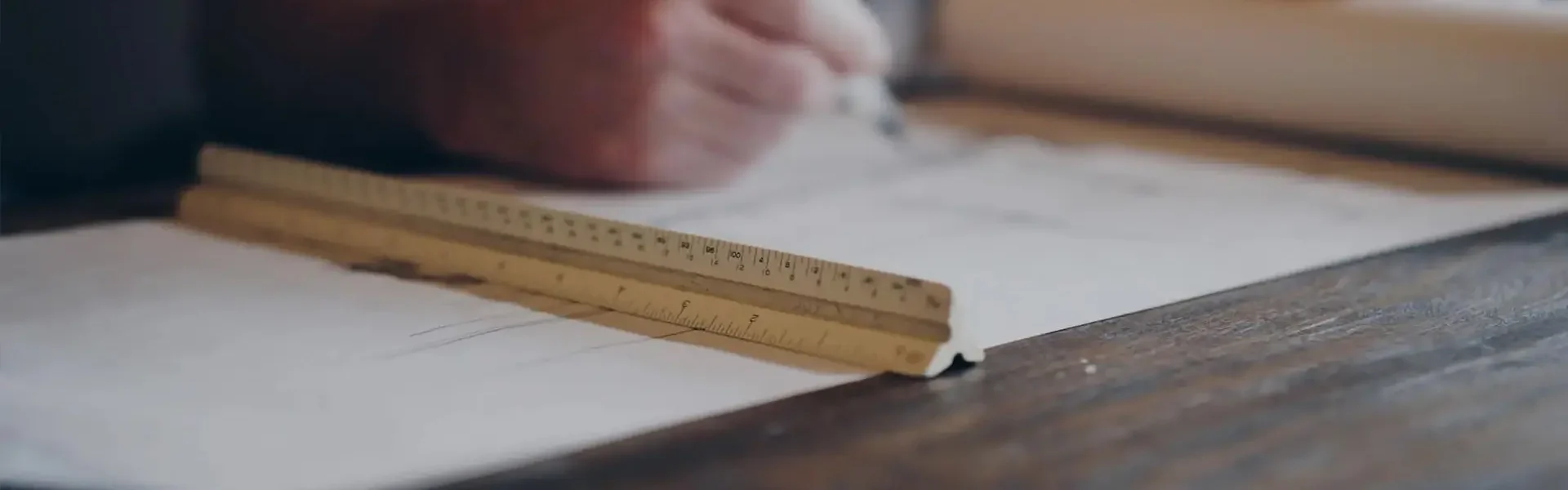 Person zeichnet auf Papier mit Lineal.