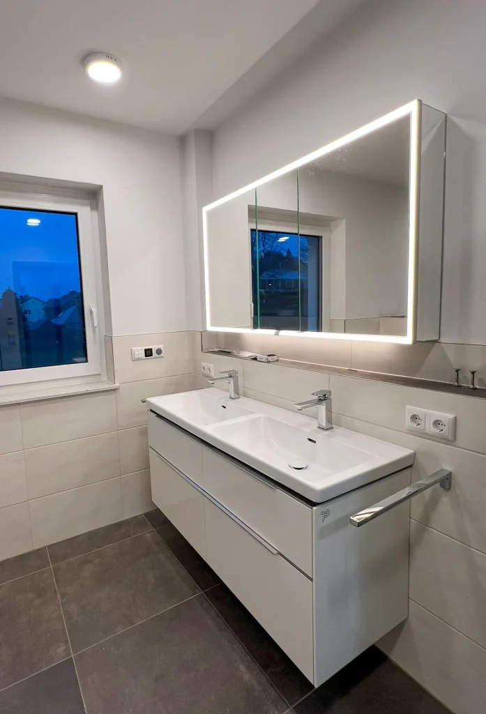 Modernes Badezimmer mit Doppelwaschbecken und beleuchtetem Spiegel.