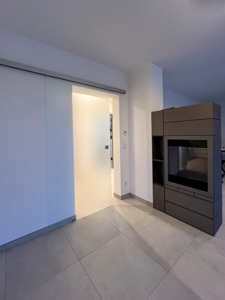Moderner Innenraum mit Schiebetür und dunklem Kamin.