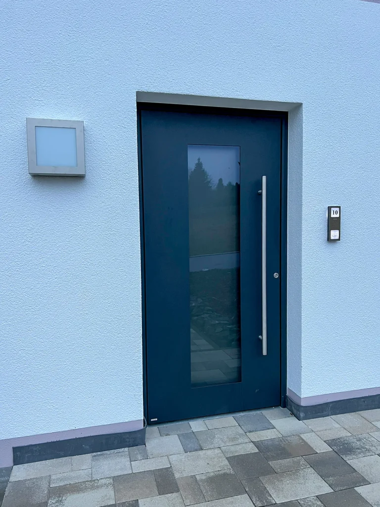 Blaue Eingangstür mit Glasfenster und Hausnummer 10.