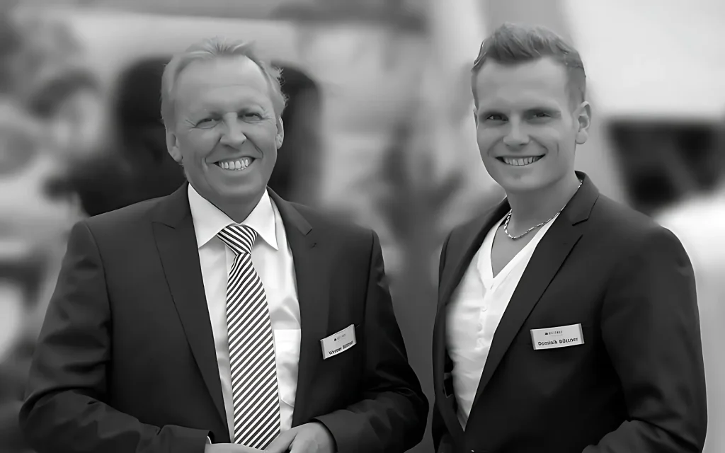 Werner und Dominik Büttner lächelnd in Anzügen.