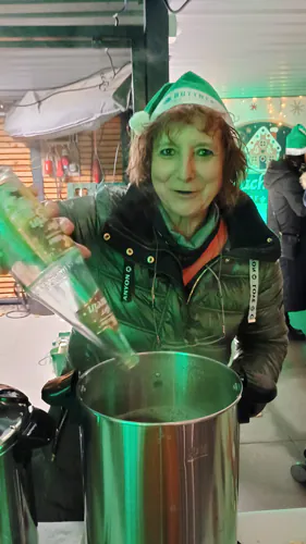 Person füllt Flüssigkeit in einen großen Behälter bei einer Veranstaltung.