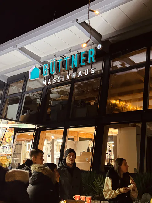 Personen vor Gebäude mit Schild "Büttner Massivhaus".