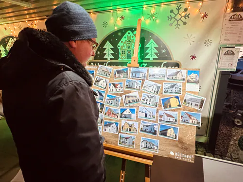 Person betrachtet Bilder auf einer Staffelei auf einem Weihnachtsmarkt.