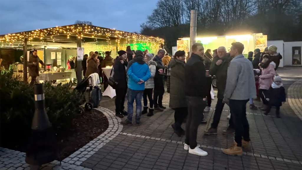Menschen versammeln sich bei einem festlichen Marktstand im Freien.