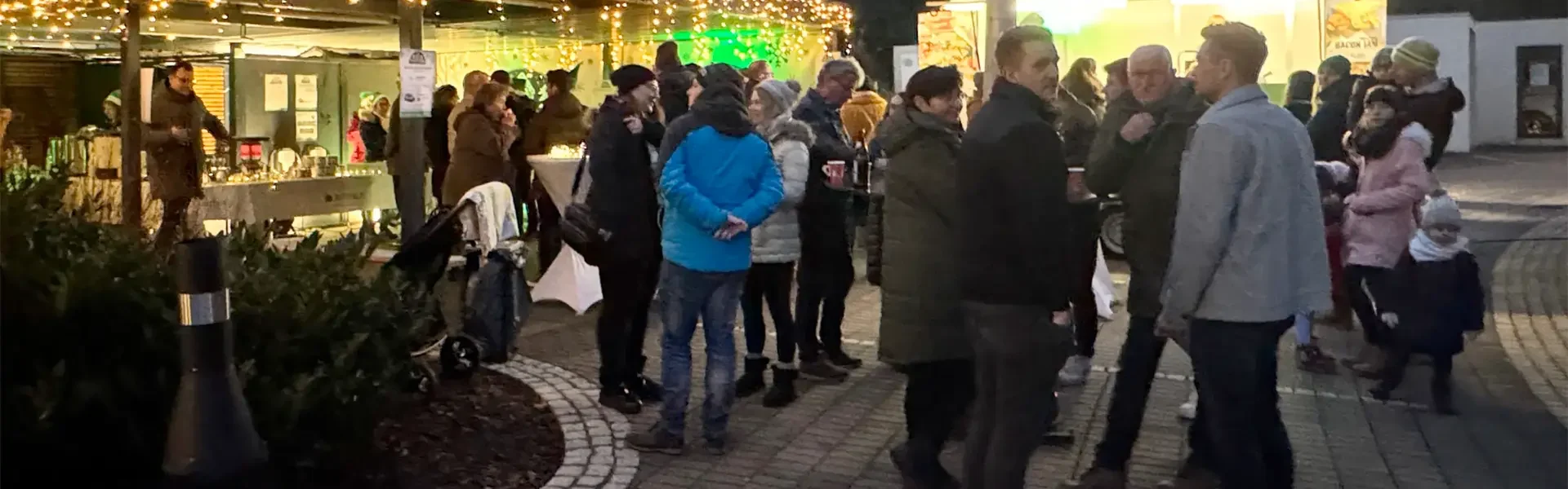 Menschen versammeln sich bei einem festlichen Marktstand im Freien.