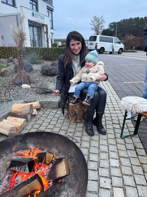 Eine Oma mit Enkelkind sitzt am Lagerfeuer und rösten Marshmallows.