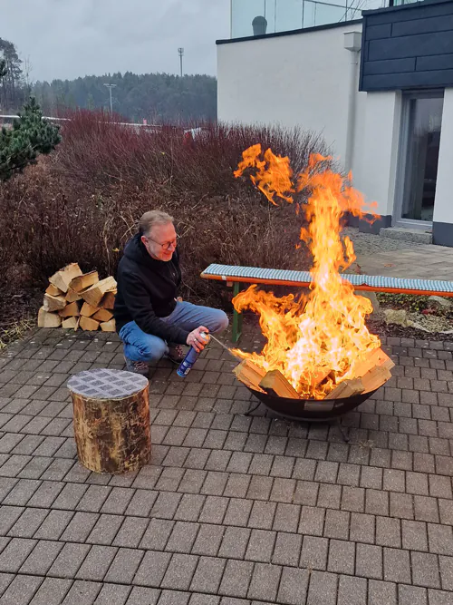 Person neben Feuerschale im Freien.