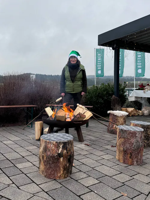 Eine Person steht bei einem Lagerfeuer im Freien.