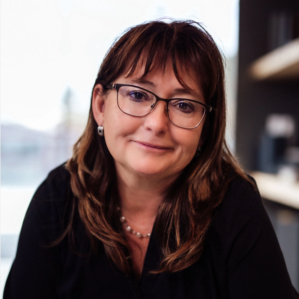 Erika mit Brille vor einem unscharfen Hintergrund.