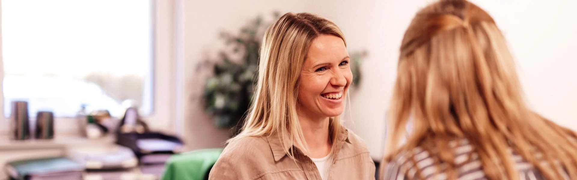 Katrin und Alisa unterhalten sich und lachen im Büro.