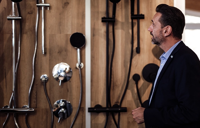 Matthias betrachtet Duscharmaturen in einer Ausstellung.