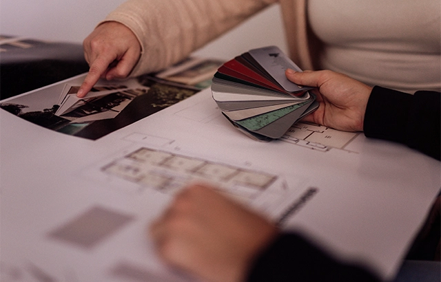 Personen betrachten Farbmuster und Baupläne.