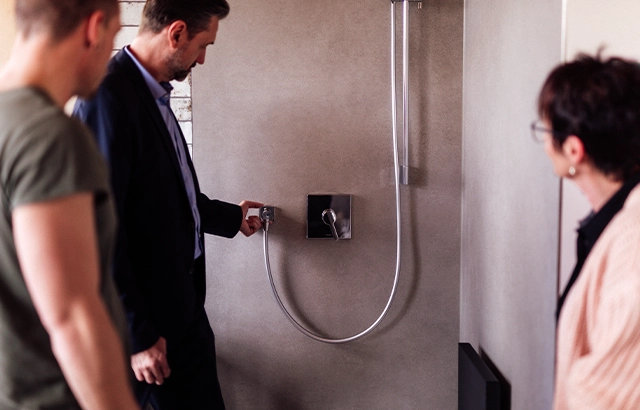 Philipp, Matthias und Manuela bei der Betrachtung einer Duscharmatur.